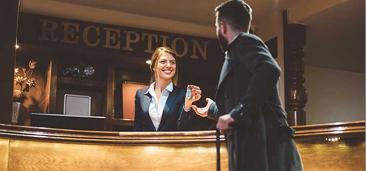 woman hotel manager hands room key to guest