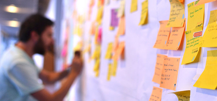 man adds postit notes to project whiteboard