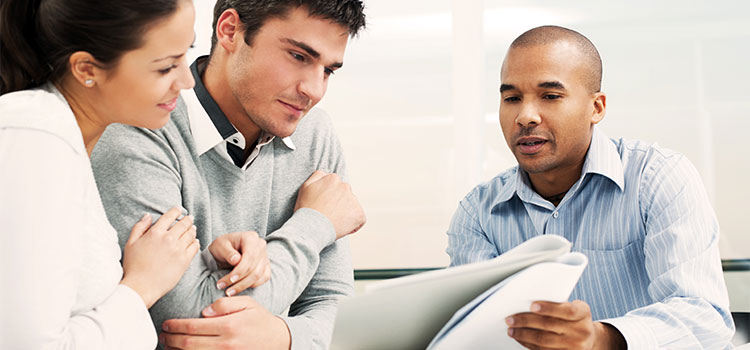 a male professional discusses paperwork with a couple