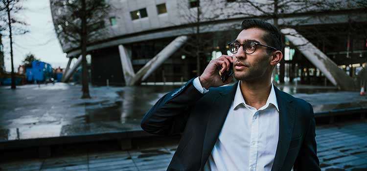 businessman talking on cell phone outside sports facility