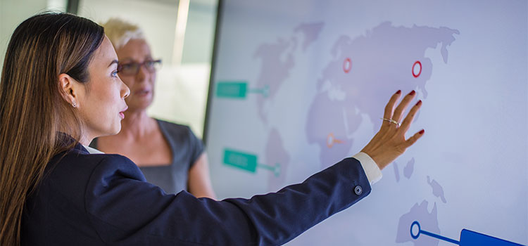 Two women talk as they look at a map on a wall