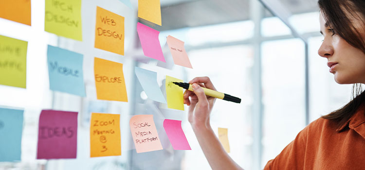A woman organizes and tracks her work on sticky notes on a board