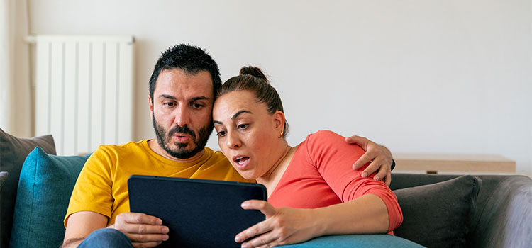 A couple sitting on a couch look at information together on a laptop