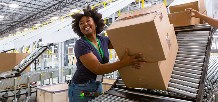 a  woman places boxes on a conveyor belt in a warehouse